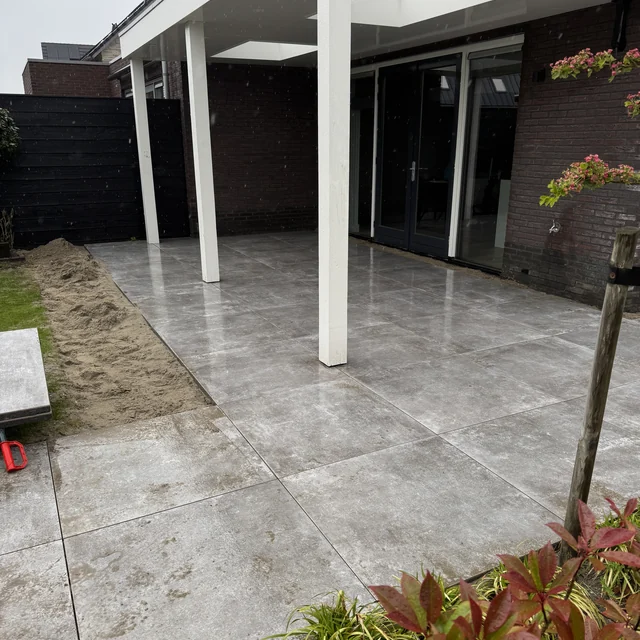 Overzicht van het afgeronde terras met de overkapping en de schuifpui